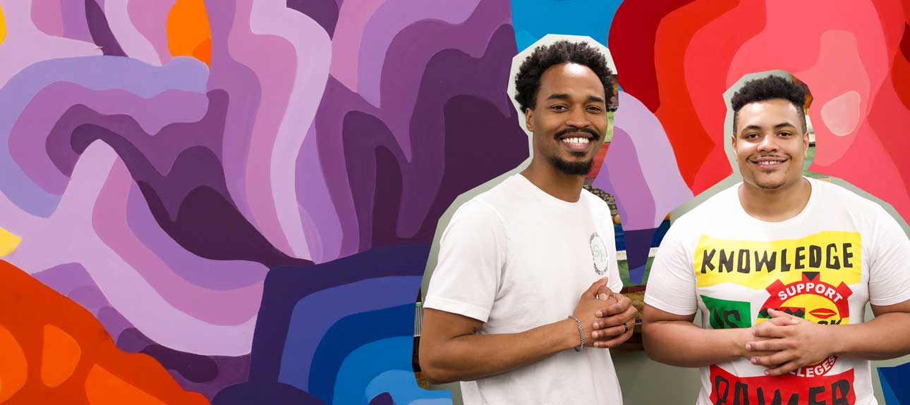 Two students in front of a colorful painted background